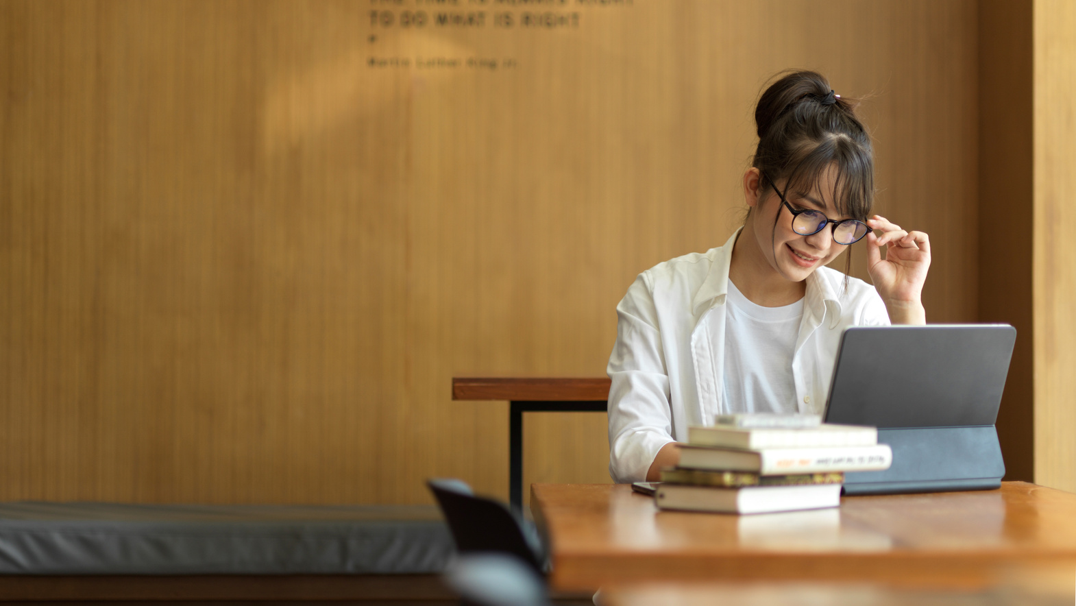 Female student research information for her thesis with books and digital tablet